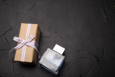 yakın plan hediye kutusu ve siyah arka planda bir şişe parfüm.