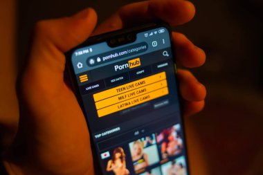 Akıllı telefon tutan ve porno sitesine göz gezdiren kişinin kırpılmış görüntüsü