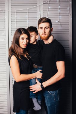 Noel 'de birlikte kameraya gülümseyen sevimli küçük oğlu olan mutlu ve genç ebeveynler.