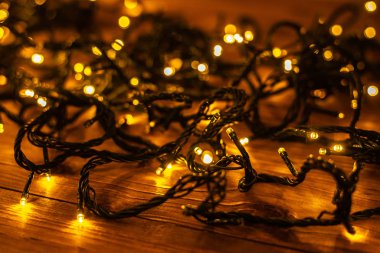 Noel arkaplanı, kahverengi ahşap arka planda aydınlatılmış şenlik çelengi. 