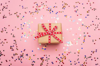 Hediye kutusunun üst görüntüsü ve pembe arkaplanda renkli konfeti