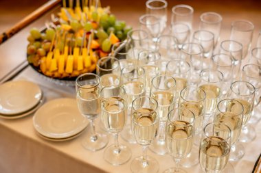 Şenlik masasında yüksek açılı şampanya kadehleri ve meyveler.  