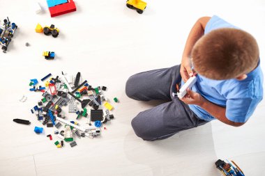 İnşaat oyuncak bloklarıyla oynayan küçük şirin bir çocuk, evde renkli oyuncaklar oynayan bir çocuk.
