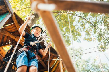 Güneşli bir yaz gününde tırmanış parkında eğlenen sevimli bir çocuğun düşük açılı görüntüsü.