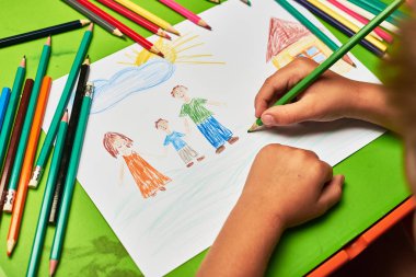 Masada aile ve ev çizen küçük çocuk.