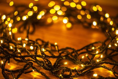 Noel arkaplanı, kahverengi ahşap arka planda aydınlatılmış şenlik çelengi. 