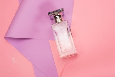 Pembe ve mor arka planda parfüm şişesinin üst görüntüsü