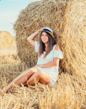 Saman balyasının yanında oturan ve kameraya gülümseyen çekici genç bir kadın. 