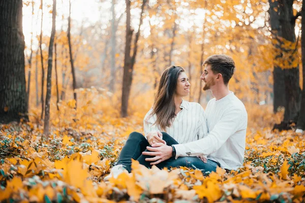 快乐的年轻夫妇坐在秋天的森林里拥抱 — 图库照片