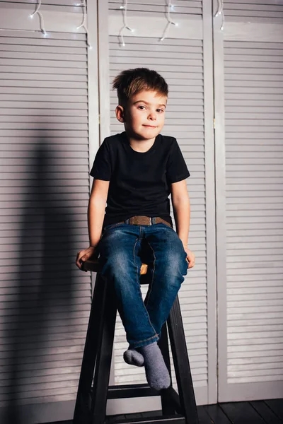 Adorable Niñito Camiseta Negra Jeans Sentado Taburete Mirando Cámara — Foto de Stock