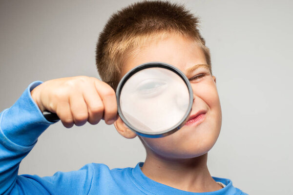 adorable child holding magnifying glass and looking at camera