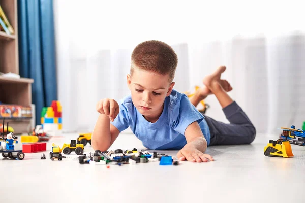 Schattig Jongetje Liggend Vloer Spelen Met Bouw Plastic Speelgoed Blokken — Stockfoto