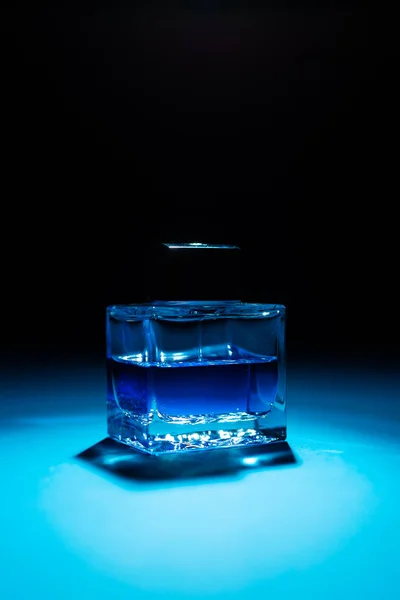青と黒の背景に男性香水のボトルのクローズアップビュー — ストック写真