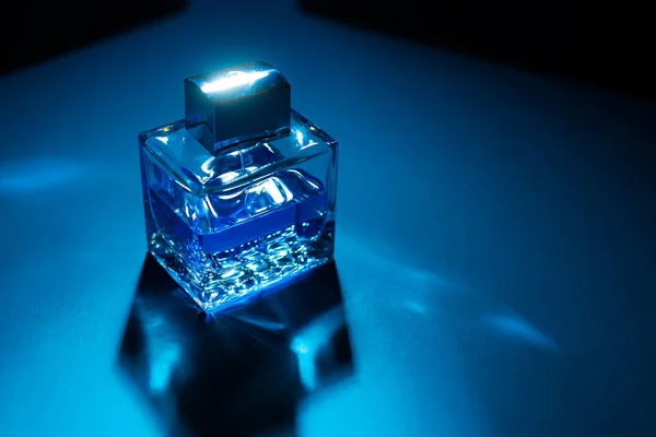 青と黒の背景に男性香水のボトルのクローズアップビュー — ストック写真