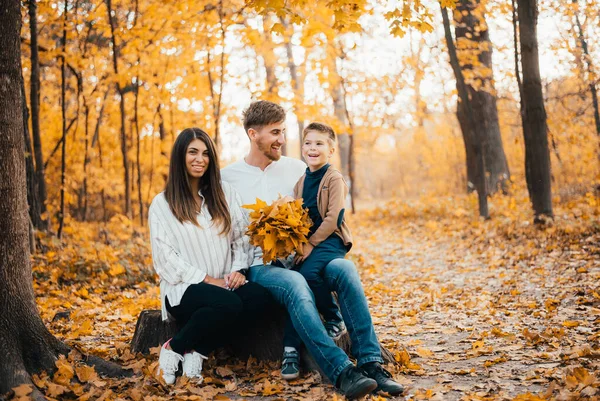 秋の公園で一緒に過ごす小さな息子を持つ美しい幸せな若い両親 — ストック写真