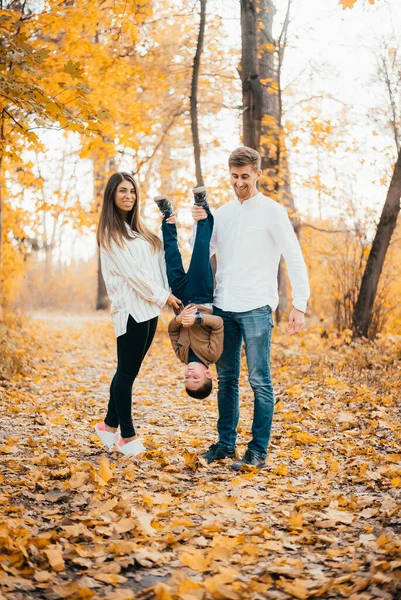 快乐的年轻父母和小儿子在秋天的公园里玩得开心 — 图库照片