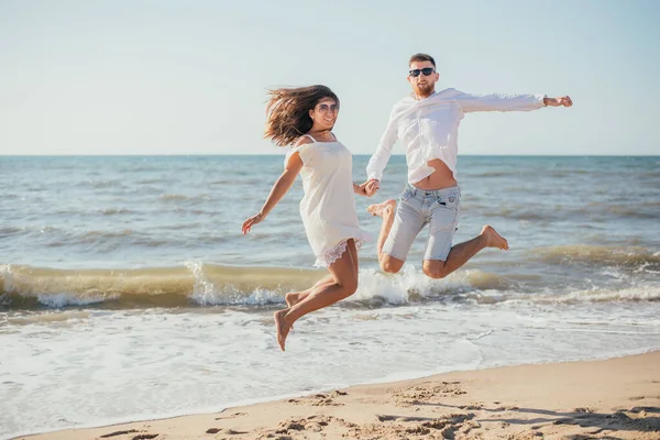 Kumlu Sahilde Birlikte Atlayan Mutlu Genç Çift — Stok fotoğraf