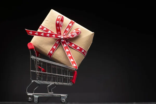 stock image shopping cart and present on dark wooden background 