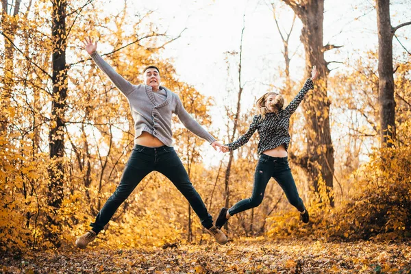 Piękna Szczęśliwa Młoda Para Trzyma Się Ręce Skacze Jesiennym Parku — Zdjęcie stockowe