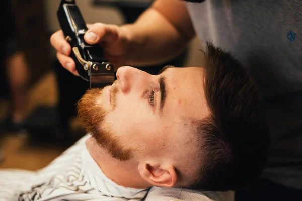 床屋の男の髪と髭を切り取った男のために髪型を作る美容師 — ストック写真