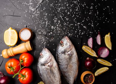 Limon dilimleri, domatesler ve baharatlı lezzetli taze balıkların üst görüntüsü.