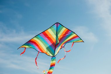 Mavi gökyüzünde uçan renkli uçurtmanın düşük açılı görüntüsü 