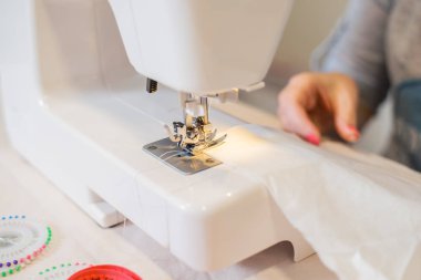 Dikiş makinesi ve terzinin kırpılmış görüntüsü.