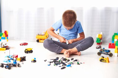 İnşaat plastik oyuncak bloklarıyla oynayan sevimli küçük çocuk, evde renkli oyuncaklar oynayan çocuk.