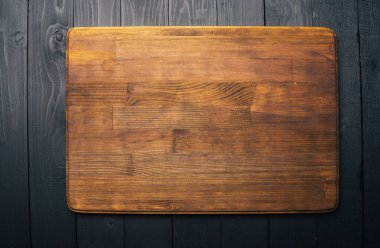 Koyu ahşap arkaplanda kahverengi kesim tahtasının yakın plan görüntüsü.