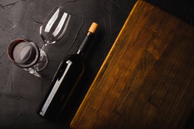 Siyah yüzeyde şarap şişesi ve bardakların üst görüntüsü