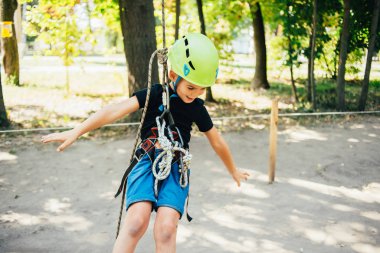 Küçük şirin çocuk yaz güneşli bir günde tırmanış parkında eğleniyor.