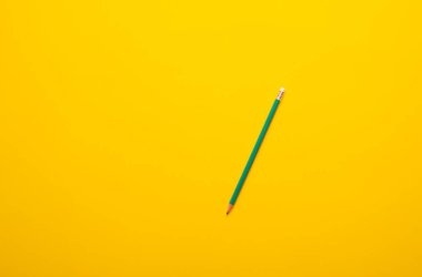 Sarı arka planda yeşil kalemin yakın plan görüntüsü. düz biçim