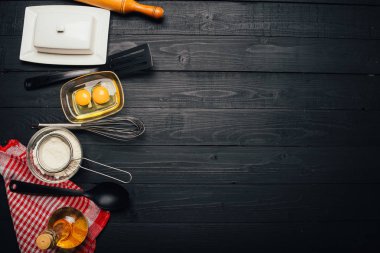 Siyah ahşap arka planda ev yapımı hamur işi için malzemeler pişiriyorum. Fırın kavramı