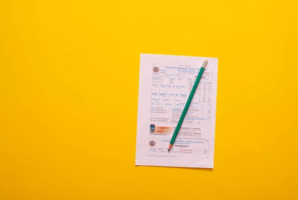 utility bill and pencil on yellow background, time to pay the bills concept