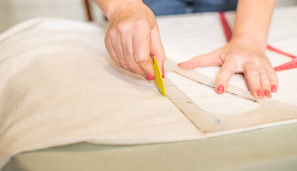 Close-up partial view of seamstress marking fabric at workplace