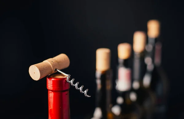 close-up view of wine bottles with corks and corkscrew on black background