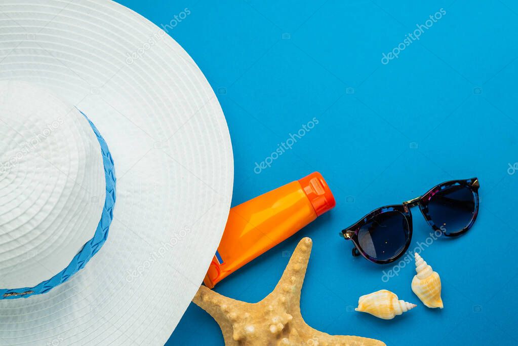 top view of starfish, sunglasses, seashells, sunscreen and hat on blue background, vacation concept  