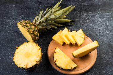 Siyah arka planda tahta üzerinde taze kesilmiş ananasın yakın plan görüntüsü.  