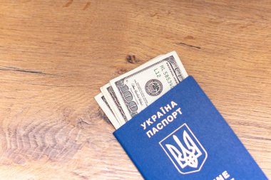 Ukrayna pasaportunun yakın plan görüntüsü ve ahşap arka planda dolar banknotları