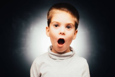 Gri arka planda poz veren duygusal sevimli çocuk