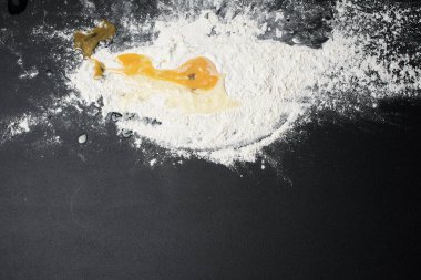 Siyah arkaplanda hamur yapmak için un ve çiğ yumurta yakın plan görüntüsü
