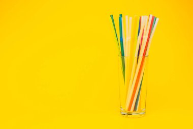 Sarı arka planda pipet içen camın yakın plan görüntüsü