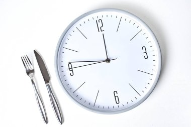 Yuvarlak saat ve çatalın beyaz zemin üzerinde bıçak ile üst görünümü   
