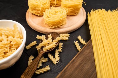 Siyah arka planda pişmemiş lezzetli İtalyan makarnasının yakın plan görüntüsü