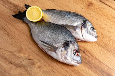 Tahta masadaki limon dilimli taze balık görüntüsü. 