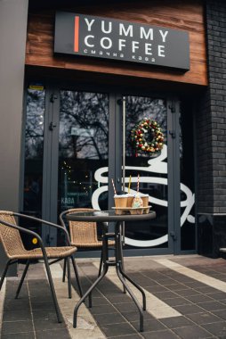 Kahve dükkanının yanındaki masada tek kullanımlık kahve fincanları ve zencefilli kurabiye var. 