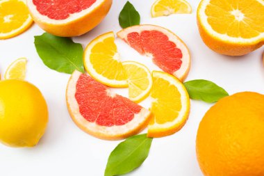 Beyaz arka planda yeşil yapraklı dilimlenmiş turunçgillerin bileşimi