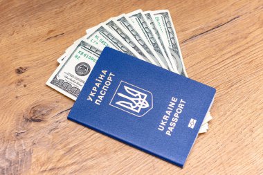 Ukrayna pasaportunun yakın plan görüntüsü ve ahşap arka planda dolar banknotları
