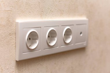 close-up view of white electric sockets on wall indoors, selective focus