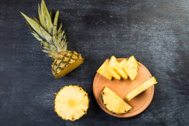 Siyah arka planda tahta üzerinde taze dilimlenmiş ananasın üst görüntüsü  